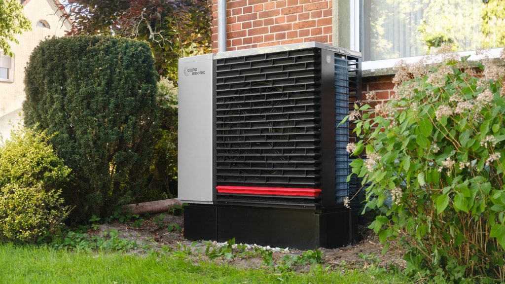 Wärmepumpen-Außengerät im Garten neben einer Hauswand