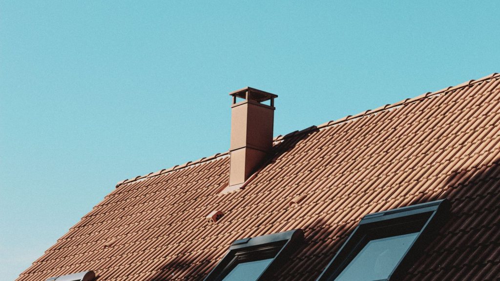 Ziegeldach mit Schornstein vor blauem Himmel