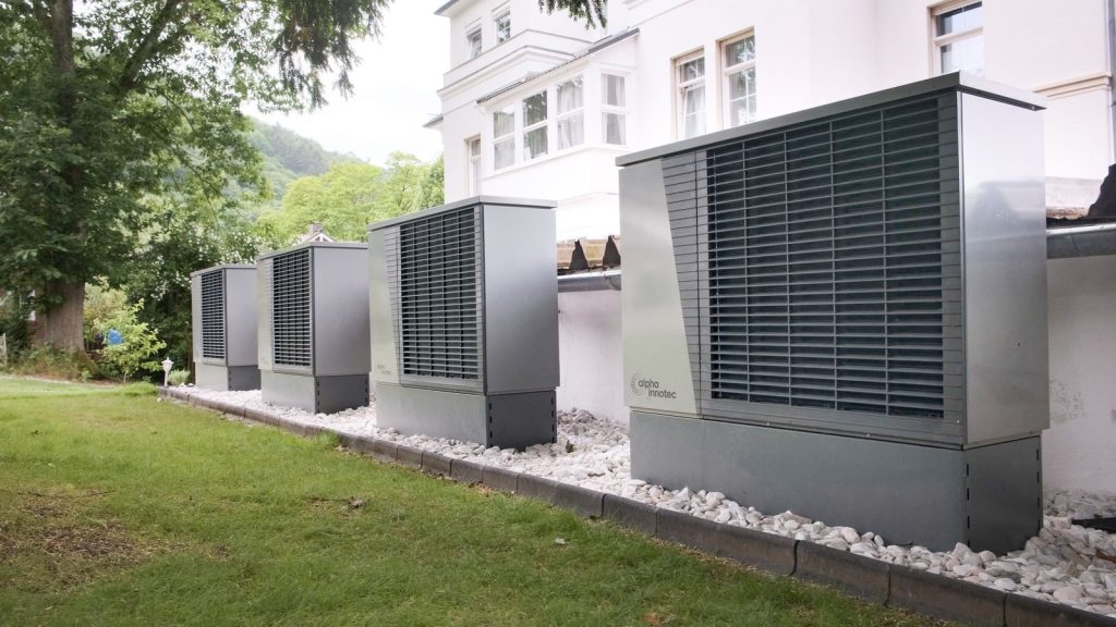 Mehrere Wärmepumpen-Außengeräte nebeneinander vor einem Haus