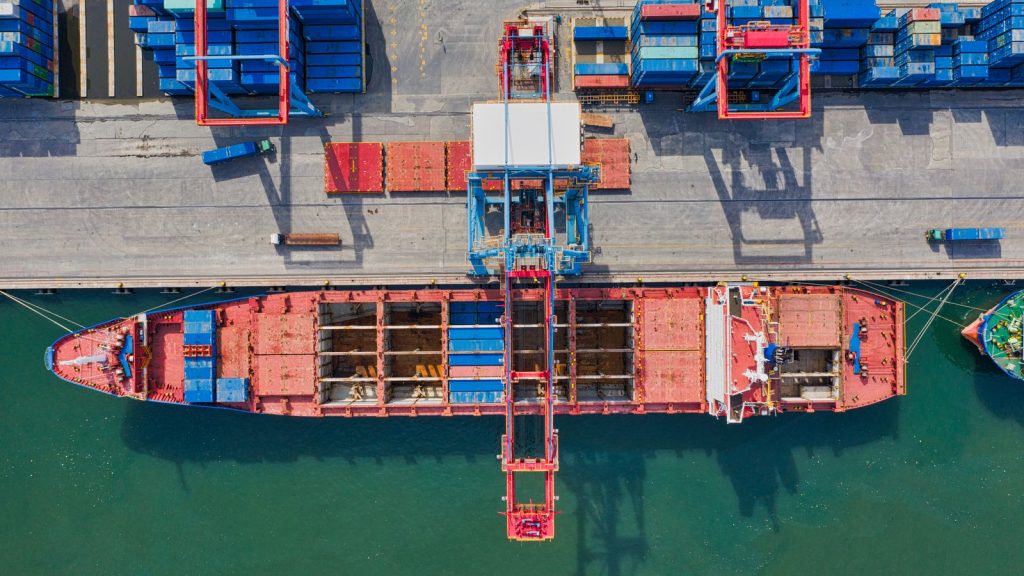 Luftaufnahme eines Containerschiffs am Kai mit Portalkränen