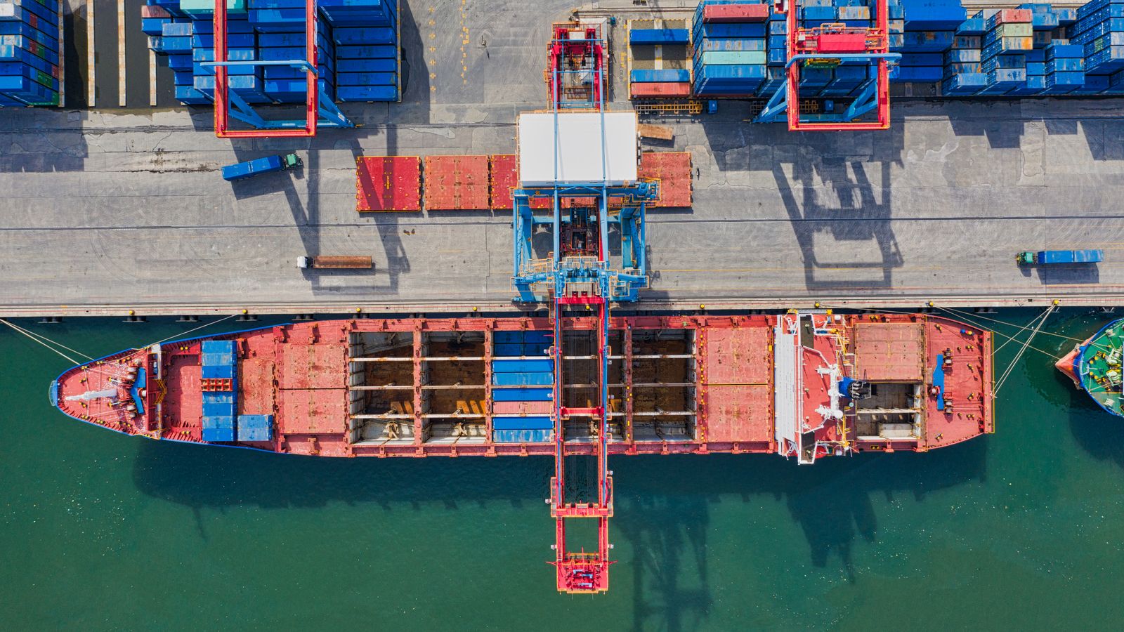 Luftaufnahme eines Containerschiffs am Kai mit Portalkränen